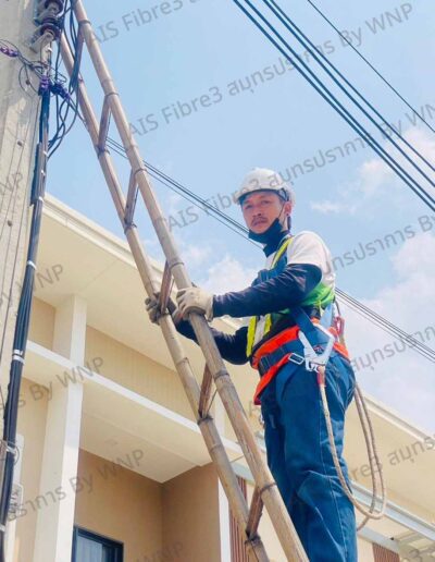 เจ้าหน้าที่ปีนเสาเพื่อติดตั้งสาย AIS Fibre ใกล้บ้านลูกค้า